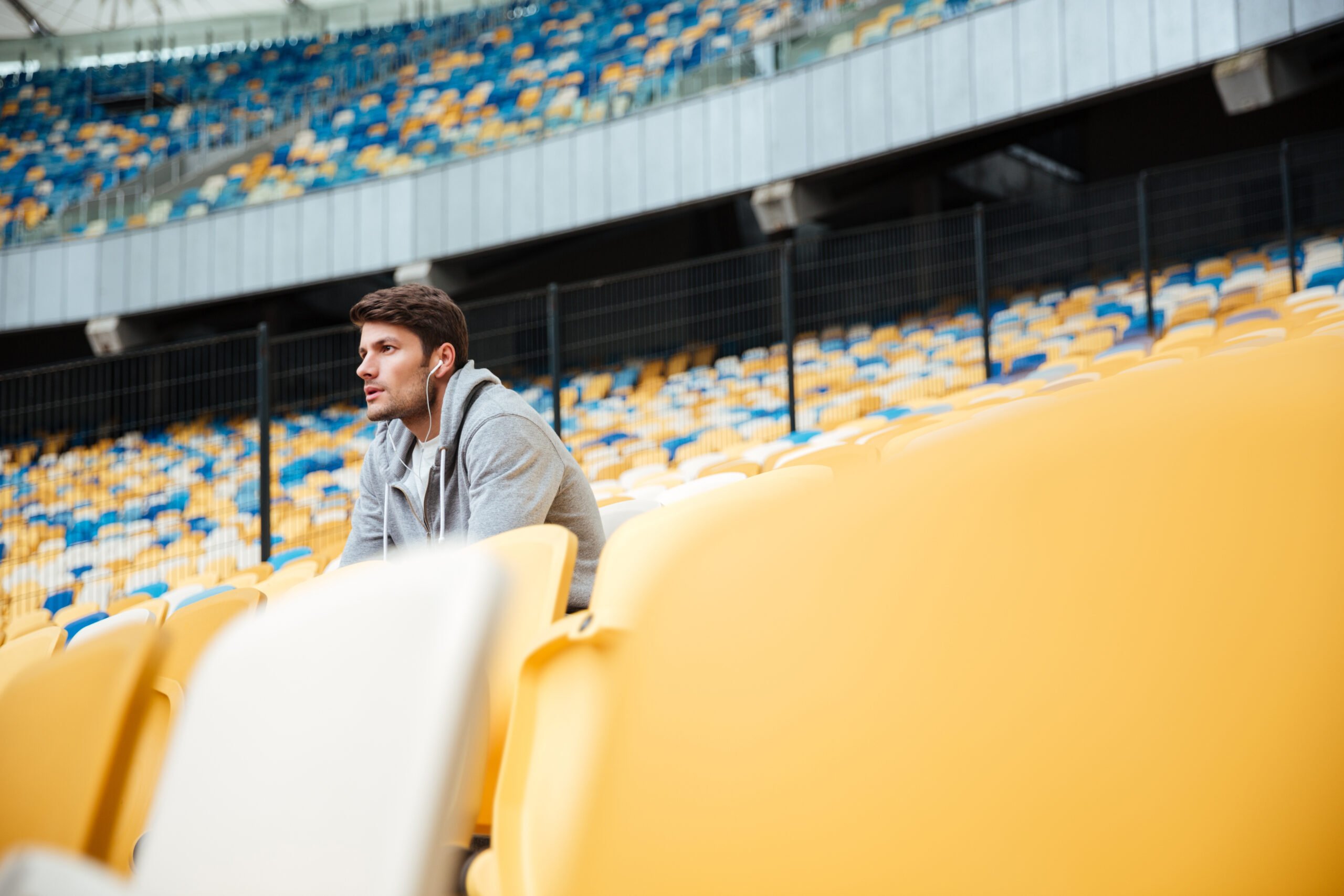 Serious young man sat at an empty sports stadium