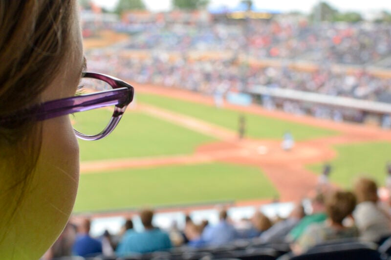 woman in glasses viewing a baseball game at stadium