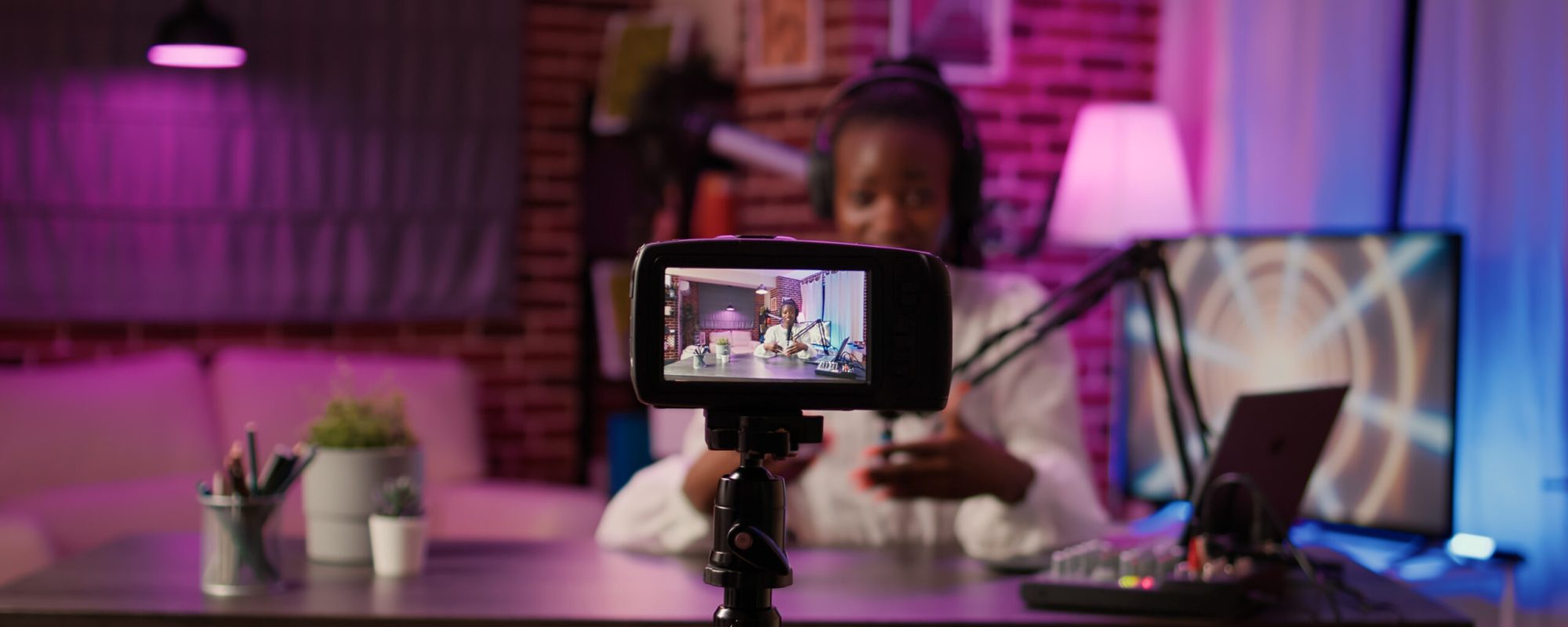 Selective focus on digital video camera screen recording african american vlogger talking to audience from home podcasting studio. Influencer filming herself doing live broadcast for social media.