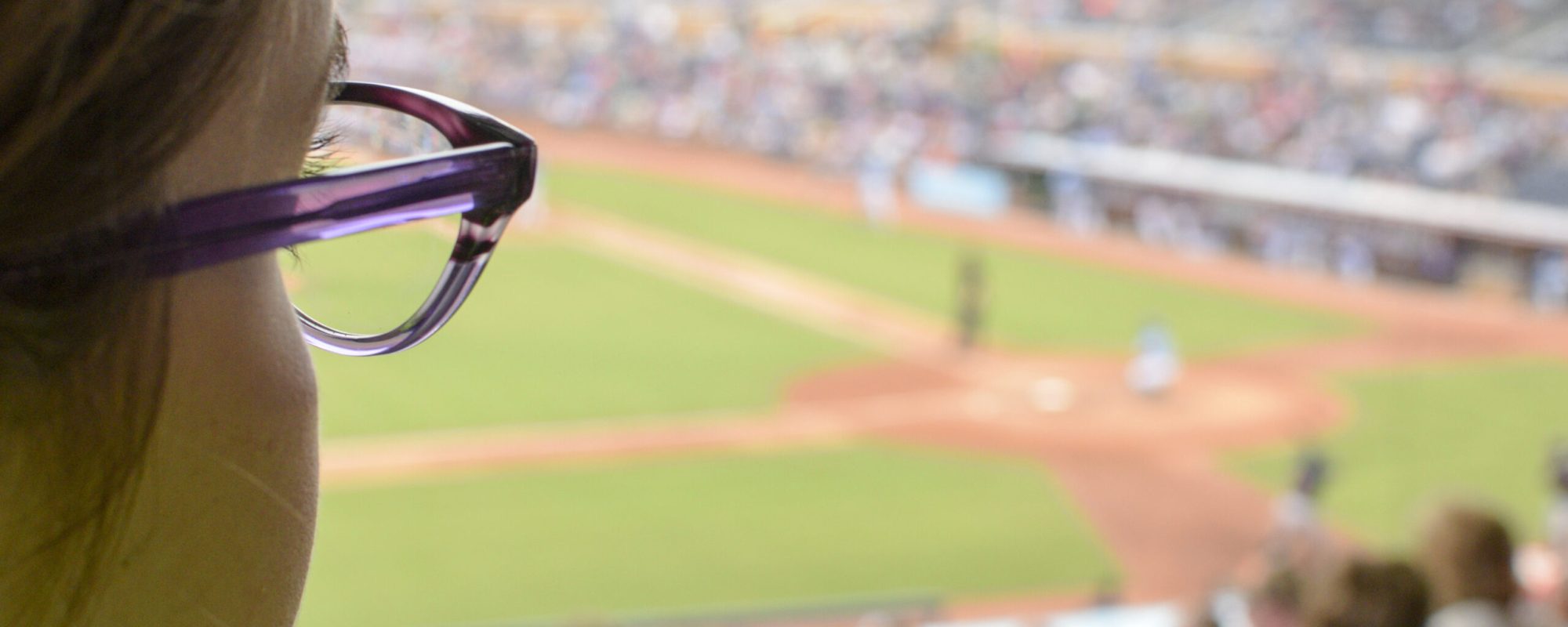 woman in glasses viewing a baseball game at stadium